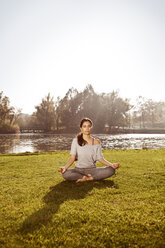 Woman with closed eyes relaxing in Lotus yoga pose - MFF003058