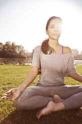 Woman with closed eyes relaxing in Lotus yoga pose - MFF003059