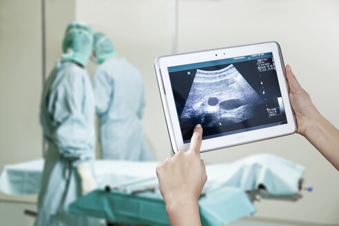 Hände halten digitales Tablet mit Ultraschallbild im Operationssaal - MFF003064