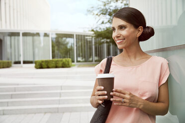 Lächelnde Frau mit Kaffee zum Mitnehmen im Freien - MFF003088