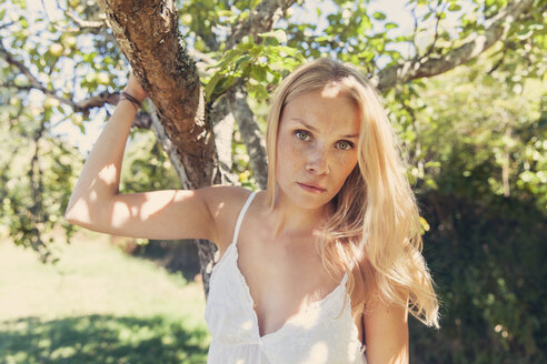 Porträt einer jungen blonden Frau am Apfelbaum - MFF003097