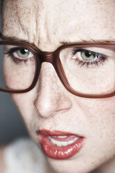 Nahaufnahme eines wütenden weiblichen Gesichts mit Sommersprossen und Brille - MFF003117