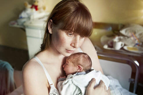 Mother holding her newborn baby in hospital room - MFF003127