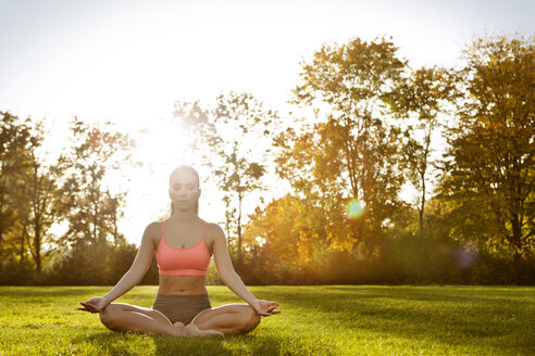 Frau mit geschlossenen Augen entspannt sich in Lotus-Yoga-Pose - MFF003167