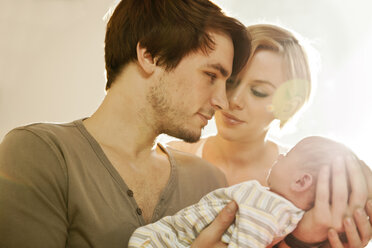 Mutter und Vater halten ihr neugeborenes Baby und betrachten es - MFF003177