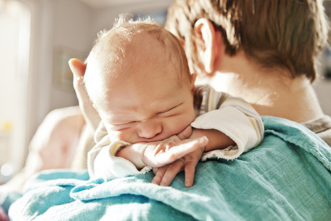 Nahaufnahme eines Vaters, der seinen neugeborenen Sohn über der Schulter hält, lizenzfreies Stockfoto