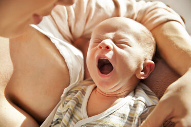 Mother holding her yawning newborn baby - MFF003185