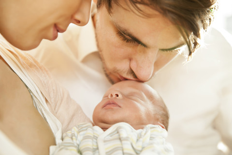 Nahaufnahme von Eltern, die ihr neugeborenes Baby küssen und halten, lizenzfreies Stockfoto