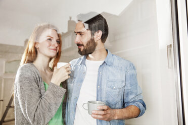 Lächelndes junges Paar bei einer Kaffeepause hinter einer Fensterscheibe - MFF003262