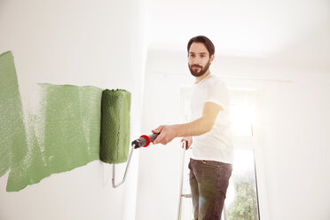Young man painting a wall green - MFF003271