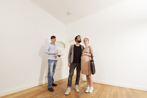 Real estate agent showing expecting parents around in a new apartment stock photo