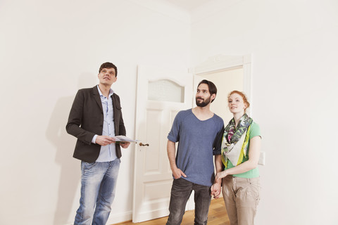 Immobilienmakler führt ein Paar in einer neuen Wohnung herum, lizenzfreies Stockfoto
