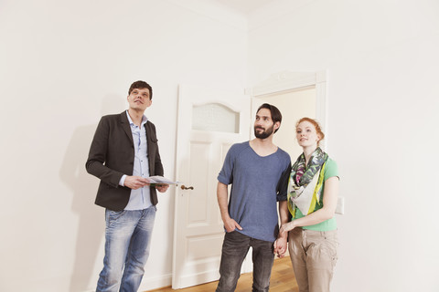 Real estate agent showing a couple around in a new apartment stock photo