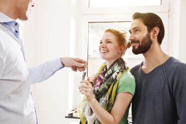 Young couple receiving house key from real estate agent - MFF003285