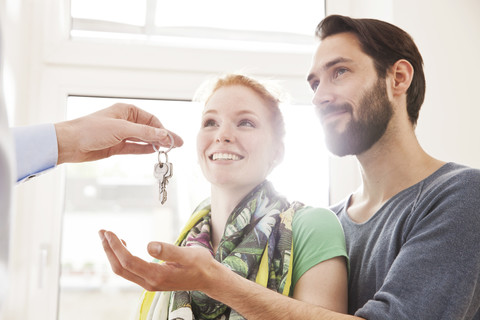 Young couple receiving house key from real estate agent stock photo