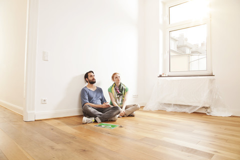 Young couple sitting on floor in empty apartment stock photo