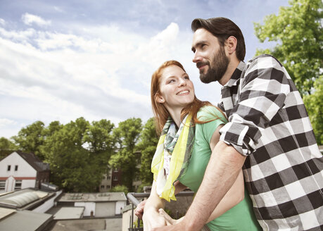 Lächelndes junges Paar auf einem Balkon in der Stadt - MFF003289