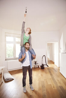 Junges Paar, das in seiner neuen gemeinsamen Wohnung eine Glühbirne austauscht - MFF003295