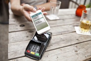 Hand mit Smartphone beim mobilen Bezahlen in einem Cafe - MFF003301