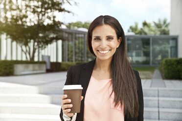 Portrait of smiling woman holding takeaway coffee outdoors - MFF003340