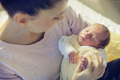 Mutter hält ihr neugeborenes Baby im Krankenhausbett, lizenzfreies Stockfoto