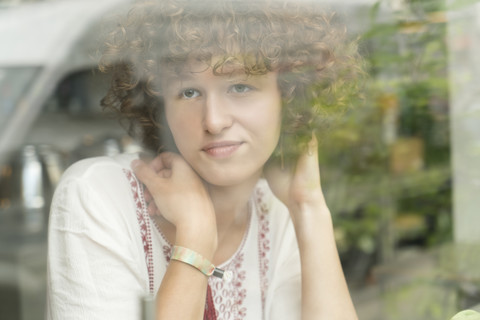 Porträt einer träumenden jungen Frau, die in einem Café sitzt und durch das Fenster schaut, lizenzfreies Stockfoto