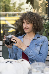 Lächelnde junge Frau mit alter Kamera in einem Straßencafé - TAMF000637