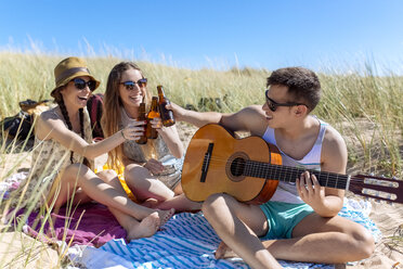 Freunde stoßen mit Bierflaschen am Strand an - MGOF002363