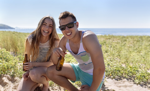 Glückliche Freunde mit Bierflaschen am Strand, lizenzfreies Stockfoto