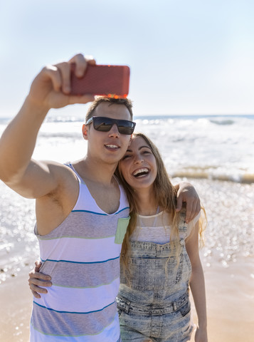 Junges verliebtes Paar macht Selfies am Strand, lizenzfreies Stockfoto