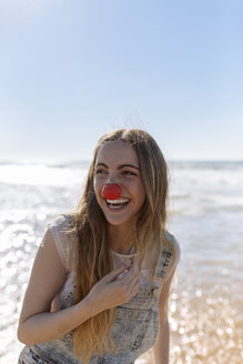 Porträt eines lächelnden Teenagers mit Clownsnase am Meer - MGOF002397