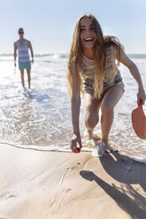 Lachendes Teenager-Mädchen, das am Strand mit Paddeln spielt - MGOF002399