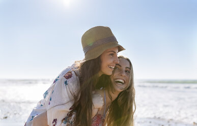 Teenager-Mädchen nimmt ihre beste Freundin am Strand Huckepack - MGOF002405