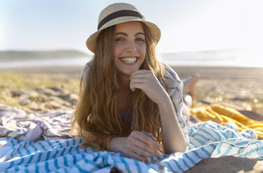 Portrait of smiling teenage girl lying on the beach - MGOF002423