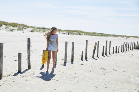 Junge Frau an Holzpfählen am Strand, lizenzfreies Stockfoto