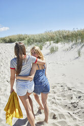 Zwei Freundinnen gehen Arm in Arm am Strand spazieren - SRYF000029