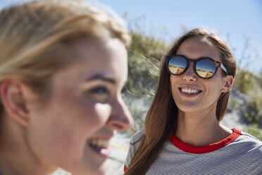 Lächelnde junge Frau mit Sonnenbrille am Strand - SRYF000031