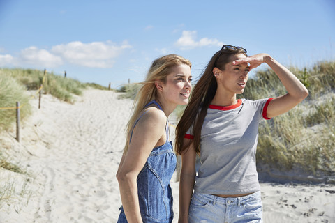 Zwei Freundinnen am Strand schauen sich um, lizenzfreies Stockfoto