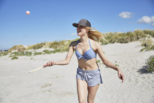 Glückliche junge Frau am Strand, die mit einem Paddel spielt - SRYF000053