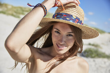 Porträt einer lächelnden jungen Frau mit Strohhut am Strand - SRYF000058