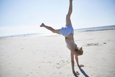 Junge Frau macht einen Handstand am Strand - SRYF000073