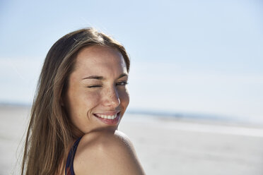 Smiling young woman twinkling on the beach - SRYF000080