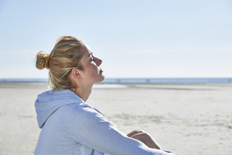 Junge Frau genießt die Sonne am Strand, lizenzfreies Stockfoto