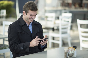 Man at outside restaurant text messaging - ZEF010064