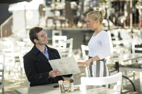 Mann und Kellnerin in einem Außenrestaurant, lizenzfreies Stockfoto
