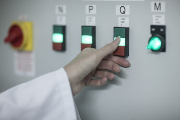 Close-up of woman switching on power switch in factory - ZEF010096