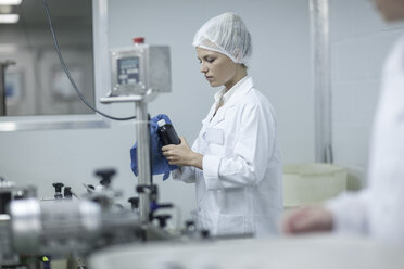 Frau in pharmazeutischer Fabrik beim Reinigen eines Kolbens - ZEF010098