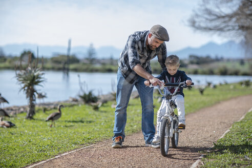 Father supporting son on bike - ZEF010210