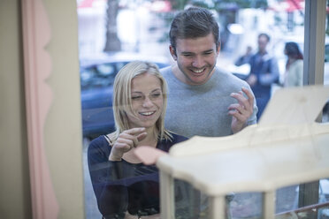 Smiling young couple looking in shop window - ZEF010244