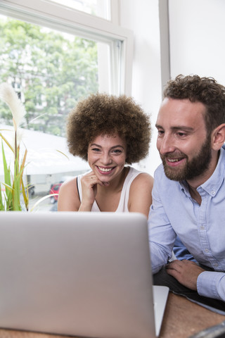 Junge Frau und Mann mit Laptop am Fenster, lizenzfreies Stockfoto